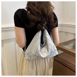 Silver metallic hobo bag with butterfly charm and chain strap shown on a model
