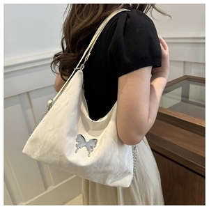 Detail of hobo bag with embossed texture, silver butterfly charm and leather strap