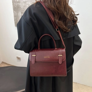 Chic burgundy flap shoulder bag with gold logo shown on model for size and fit