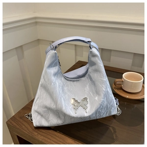 Detailed view of the light blue handbag with marble pleats and silver butterfly decor