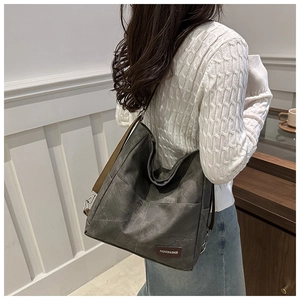 Detail of dark grey canvas tote bag with adjustable brown strap and decorative leather tag