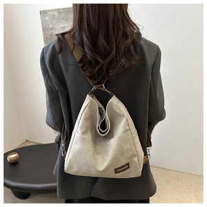 Close-up of leather label on light grey minimalist tote bag with brown shoulder strap