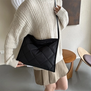 Sac fourre-tout noir matelassé avec coutures en losange porté par un mannequin en intérieur
