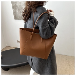 Close-up of caramel brown pebble leather tote bag worn by model in a modern interior