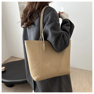 Close-up of beige tote bag featuring pebbled leather texture and fashion brand embossing