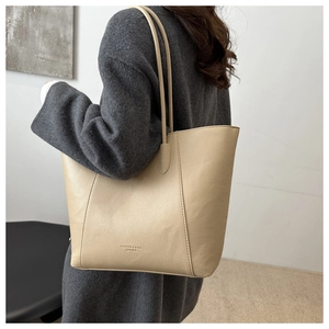 Close-up of beige leather tote bag with embossed fashion text and long shoulder straps