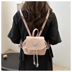 Détail du mini sac à dos en similicuir rose avec plaque mode et cordon à perles