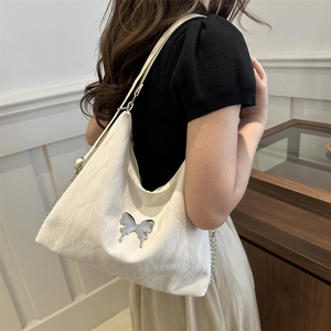 White hobo shoulder bag with silver butterfly charm and chain strap on a model