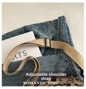 Detail of adjustable beige woven strap and black slider on leopard print crossbody bag