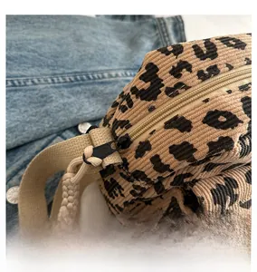 Detailed close-up of smooth black metal zipper on leopard print corduroy crossbody bag