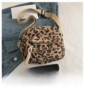 Detail of leopard print corduroy crossbody bag with adjustable strap and front pocket