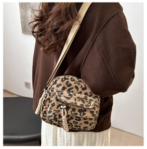 Close-up of leopard print corduroy crossbody bag with woven strap on female model