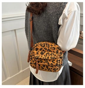 Detail of leopard print corduroy crossbody bag with adjustable strap worn by a model