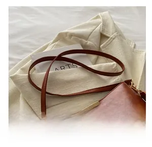 Detail view of brown lychee-grain leather bucket bag with gold hardware on white blazer