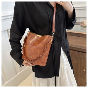 Close-up of caramel brown bucket bag featuring gold hardware and LANGE & SHIJIA branding