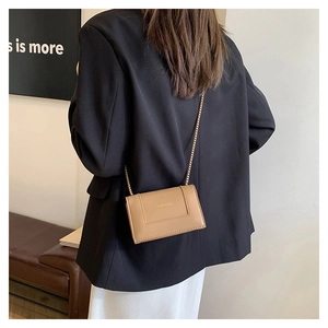 Back view of khaki chain crossbody bag worn with a black blazer and white dress
