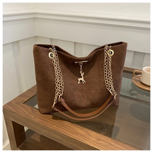 Close-up of brown suede tote bag featuring layered gold chain and deer pendant charm