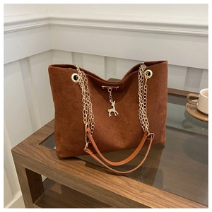 Detail of caramel suede tote bag with golden deer pendant and metallic chain strap