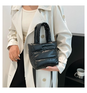 Chic black quilted puffer handbag with fluffy texture shown against a white coat