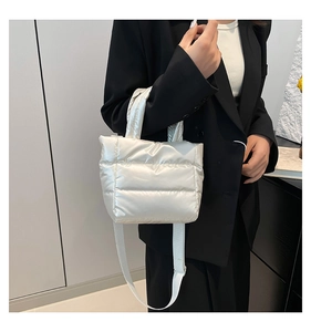 Close-up of pearl white quilted bucket bag with adjustable strap on a black blazer