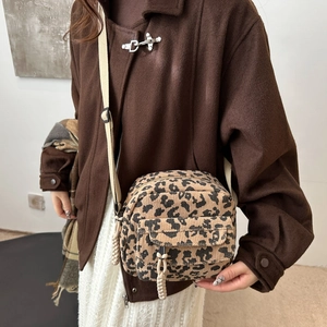 Sac bandoulière en velours côtelé léopard avec sangle réglable porté par un mannequin élégant
