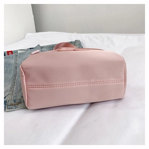 Detailed view of reinforced double stitching on the base of a pink nylon shoulder bag