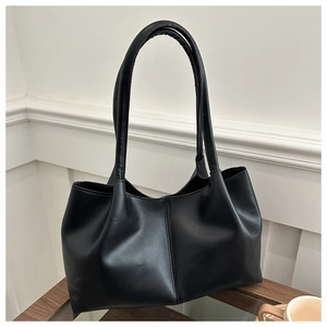 Detail of minimalist black tote bag with vertical center stitching on matte leather texture