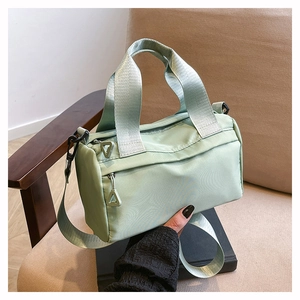 Close-up of light green nylon shoulder bag featuring a front zipper pocket and fabric handles