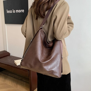 Deep brown large capacity faux leather tote bag with wide strap worn by a model