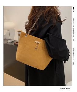 Detail of mustard yellow suede tote with gold chain strap and elk charm pendant