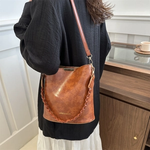 Retro brown leather bucket bag with braided handle and crossbody strap for women