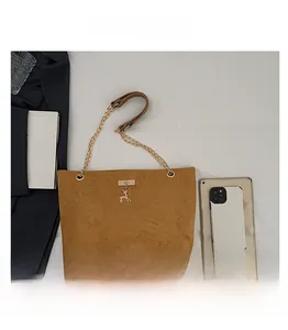 Brown suede tote bag with golden chain strap and deer pendant detail for size reference