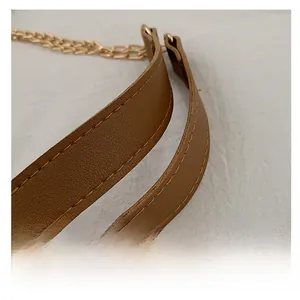 Close-up of brown leather shoulder strap with gold chain and contrast stitching detail
