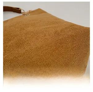 Macro detail of brown suede texture and golden metal hardware on vintage shoulder bag