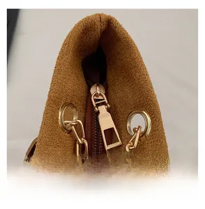 Close-up of golden metal zipper and chain buckle on vintage brown suede tote bag