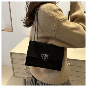 Détail du sac bandoulière en daim noir avec boucle argentée et bandoulière à rivets