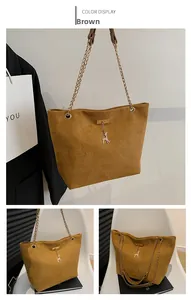 Close-up of brown suede tote bag featuring a gold chain strap and deer charm detail