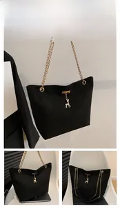 Detail view of black tote bag with gold chain strap and elegant deer metal charm