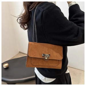 Détail du sac bandoulière en daim caramel avec chaîne dorée et fermoir à rivets