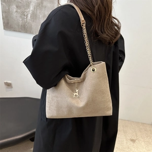 Retro khaki suede shoulder bag with gold chain strap and deer pendant on black trench coat