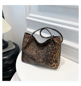 Macro detail of high-capacity leopard print tote bag on minimalist white pedestal