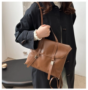 Detail of vintage brown tote bag with metal buckles and leather straps on black coat