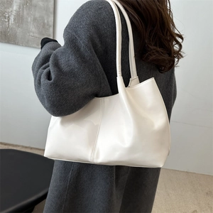 Minimalist white leather tote bag with vertical seam detail shown as a shoulder bag