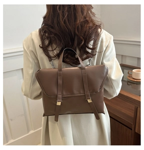 Detail of coffee brown leather backpack showing gold metal buckles and vintage texture