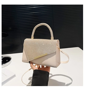 Detail of cream white handbag with sparkling rhinestone flap and golden metal bar