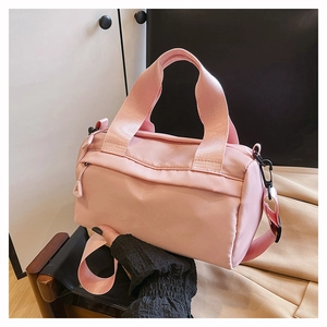 Primer plano del bolso cilíndrico de nailon rosa con correa extraíble y textura resistente