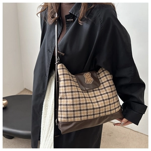 Détail du sac bandoulière en toile à carreaux avec ours brodé et rabat en cuir