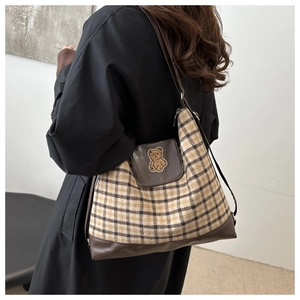 Détail du sac cabas vintage en toile à carreaux avec bordure en cuir et écusson d'ours