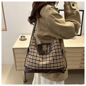 Détail du sac cabas en toile écossaise avec finitions en cuir brun et broderie d'ours