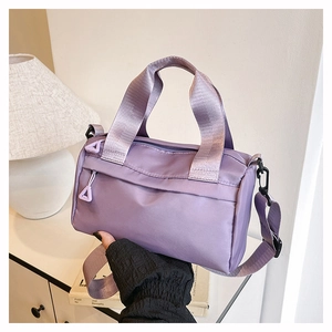Detalle del bolso bandolera de nailon morado con asa ancha de cincha y cremallera única